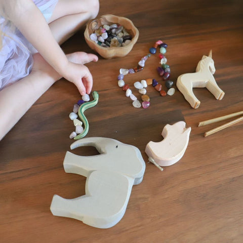 Close-up of little girl playing with crystal and wooden toy animals.