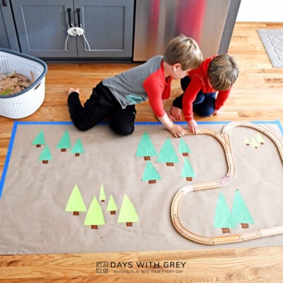Preschoolers working together to build a wooden train track.