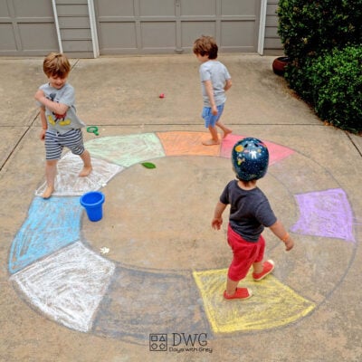 Three kids marching outside around a chalk colored circle.