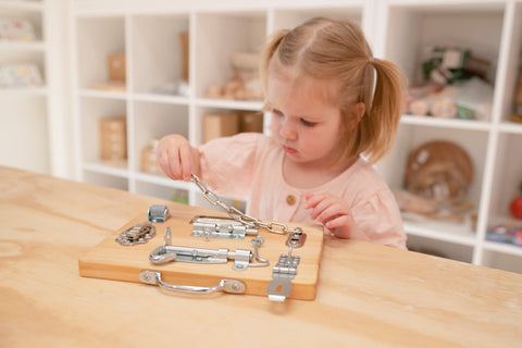Little girl playing with Montessori lock board wooden toy