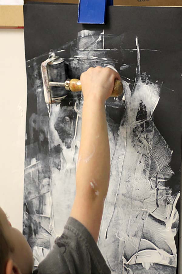 A child expresses the rotation play schema by rolling a paint roller on a wall