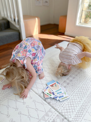 Two little girls doing yoga poses with quality flash cards.
