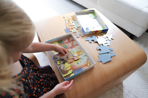 Little girl play with a Ravensburger puzzle.