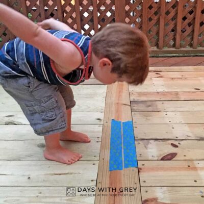 Toddler getting his body ready to jump over two lines of painter's tap