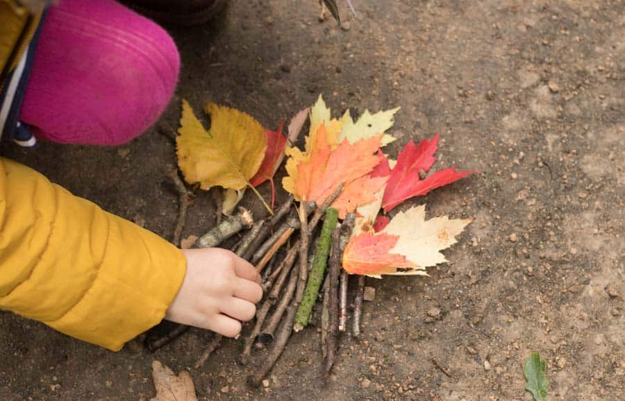 Child arranging sticks and leaves in picture of bonfire