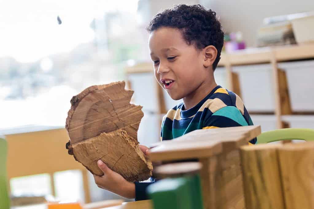 A preschooler plays with tree blocks in the block center.