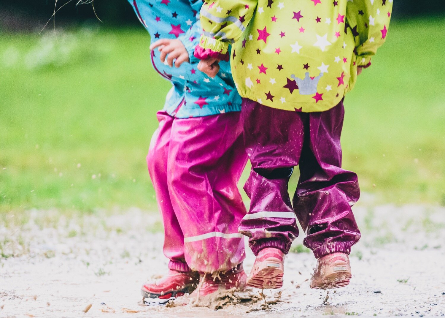 Kids jumping in puddles wearing rain boots and splashing mud. This movement activity that is a tip for helping to develop language.