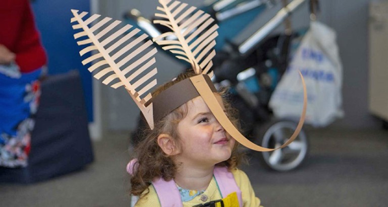 A young girl wearing a paper moth headdress