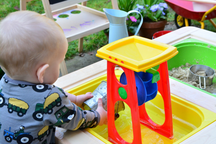 Outside water play at How we Montessori  17 months  water wheel and sand table
