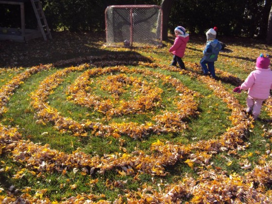 toddlers walking in fall leaf labyrinth in backyard