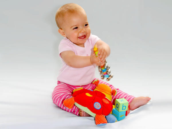 baby holding toy sitting and smiling