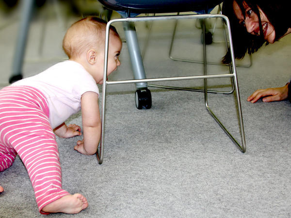 smiling baby crawling under chair